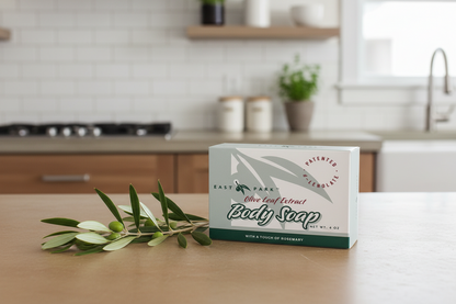 Bar of soap with packaging on a kitchen counter, featuring olive leaves.